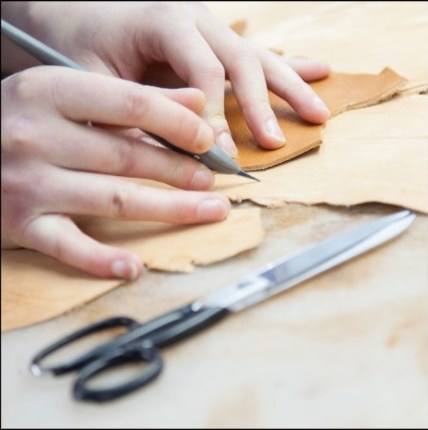 Leather being marked and cut at an artisan workbench